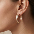 Boucles d'oreilles créoles en or rose 18k serties de pierres - bijou porté par une mannequin