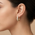 Boucles d'oreilles créoles en or jaune 18k serties de pierres, ajourées - bijou porté par une mannequin