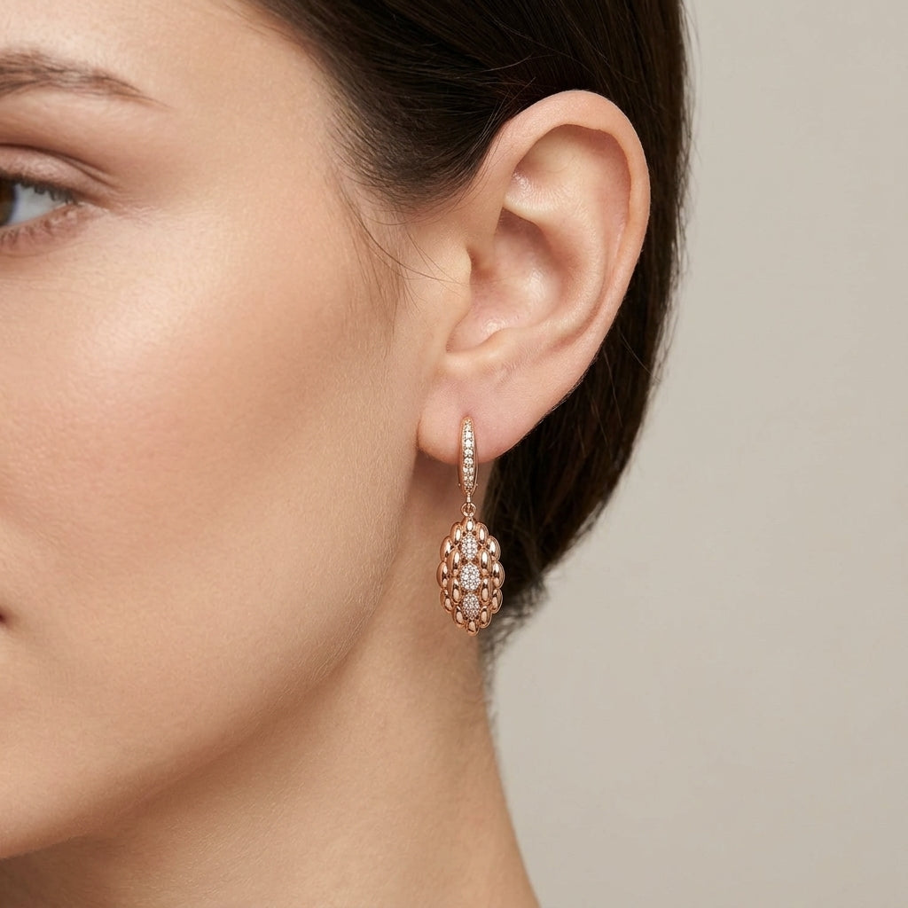 Boucles d'oreilles pendantes gouttes ajourées en or rose 18k serties de pierres - bijou porté par une mannequin