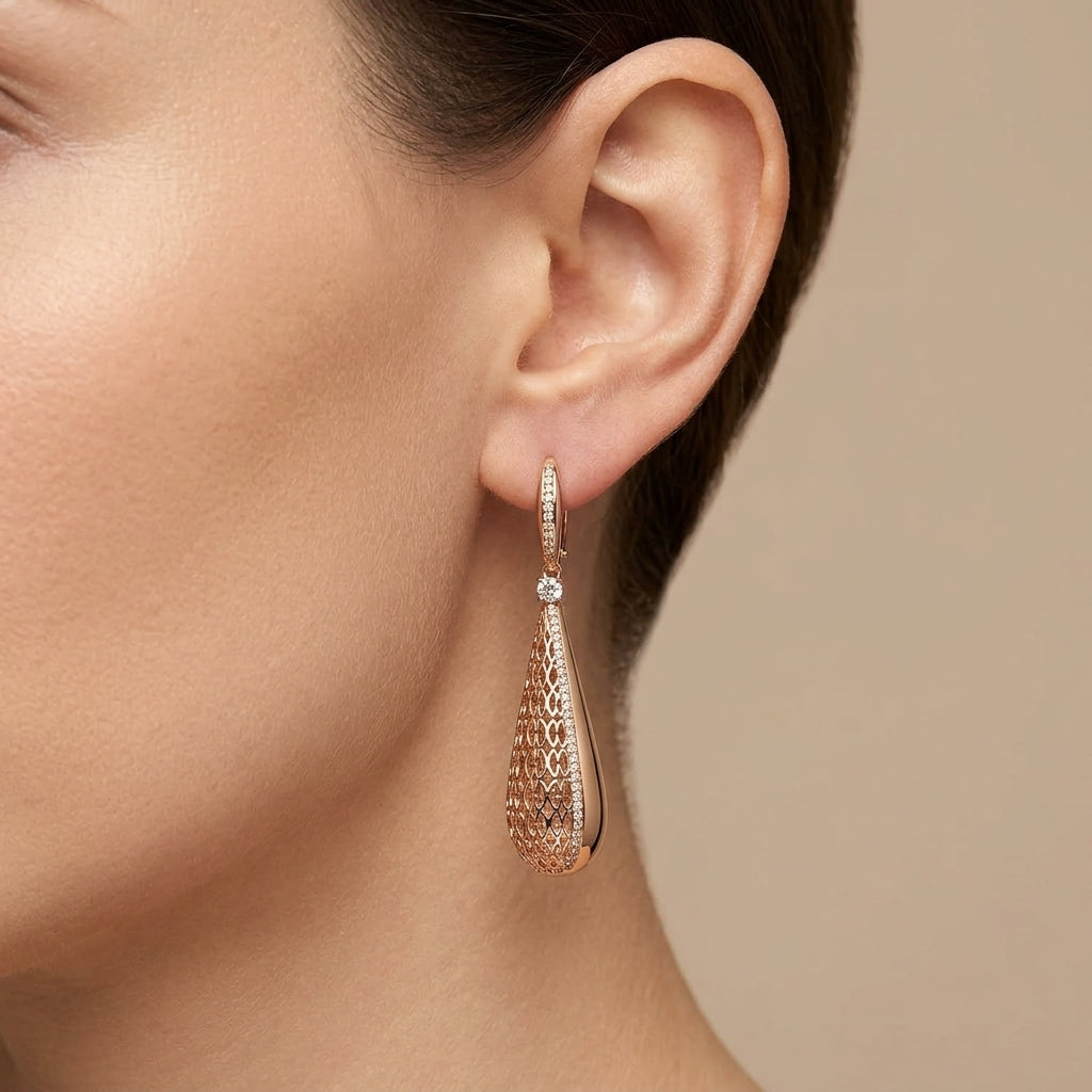 Boucles d'oreilles pendantes gouttes ajourées en or rose 18k serties de pierres - bijou porté par une mannequin