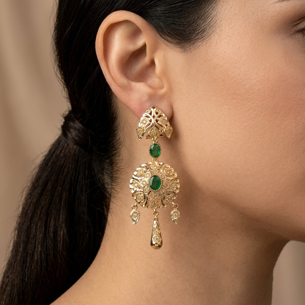 Boucles d'oreilles pendantes beldi ajourées en or jaune 18k serties de pierres vertes synthétiques - bijou porté par une mannequin