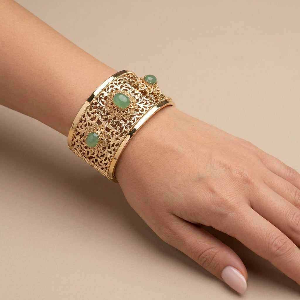 Bracelet manchette beldi ajourée en or jaune 18k sertie de pierres vertes synthétiques - bijou porté par une mannequin