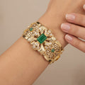 Bracelet manchette beldi ajourée en or jaune 18k sertie de pierres vertes synthétiques - bijou porté par une mannequin