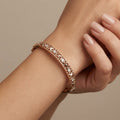 Bracelet jonc ajouré en or rose 18k serti de pierres - bijou porté par une mannequin