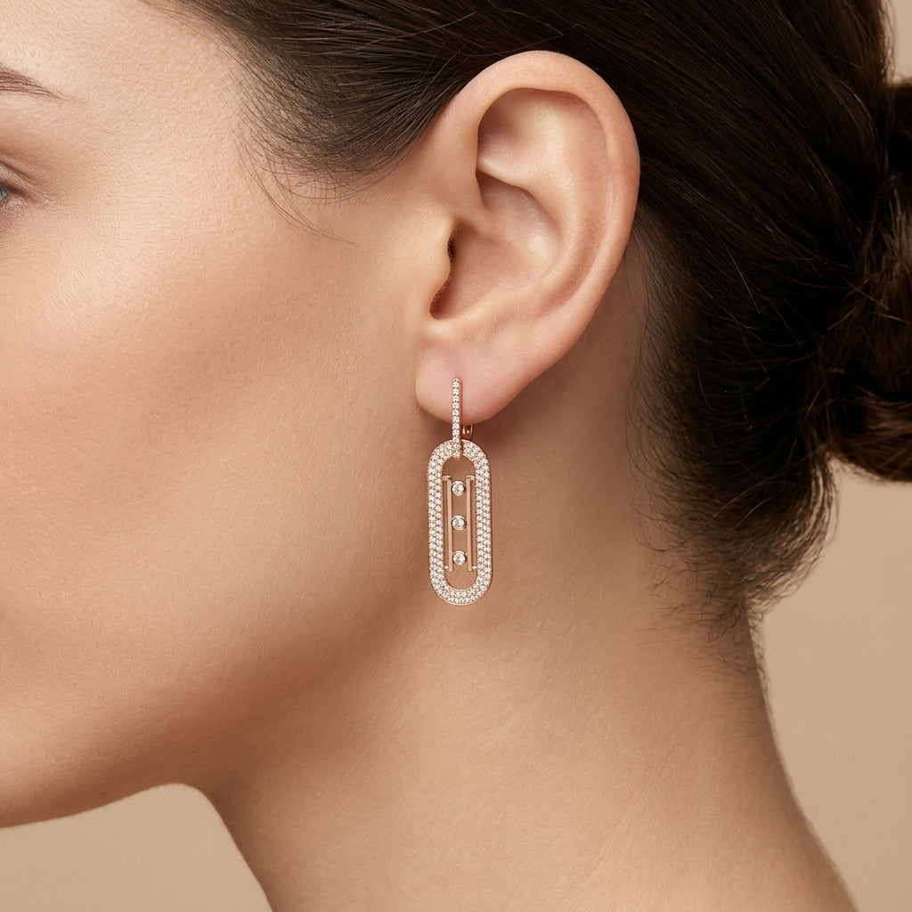 Boucles d'oreilles pendantes en or rose 18k ovales sertis de pierres - bijou porté par une mannequin