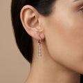 Boucles d'oreilles pendantes en or rose 18k ovales sertis de pierres - bijou porté par une mannequin