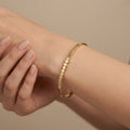 Bracelet jonc fin en or jaune 18k pastilles rondes - bijou porté par une mannequin