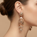 Boucles d'oreilles pendantes beldi rosaces ajourées en or rose 18k serties de pierres - bijou porté par une mannequin