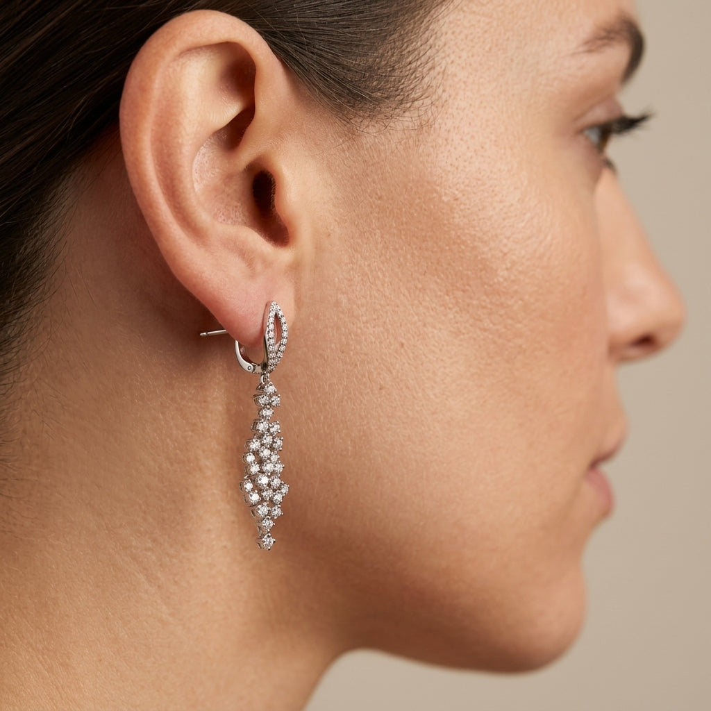 Boucles d'oreilles pendantes en or blanc 18k pavées de pierres - bijou porté par une mannequin