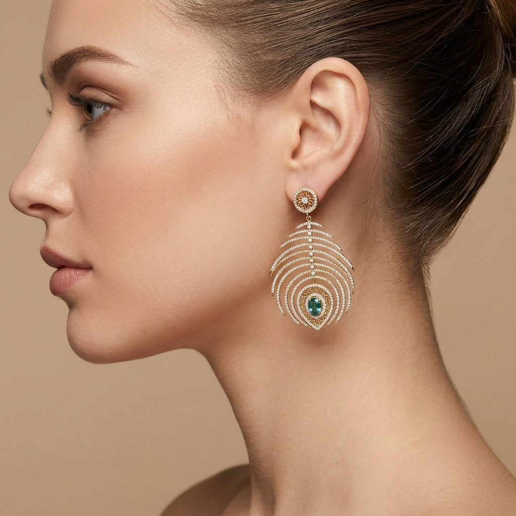 Boucles d'oreilles pendantes plumes de paon en or jaune 18k serties de pierres, pierres vertes - bijou porté par une mannequin