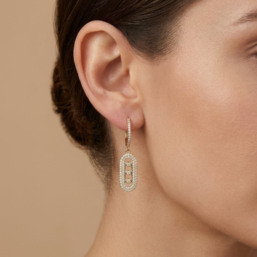 Boucles d'oreilles pendantes en or jaune 18k ovales sertis de pierres - bijou porté par une mannequin
