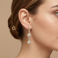 Boucles d'oreilles pendantes en or jaune 18k motifs ronds pavés de pierres - bijou porté par une mannequin