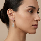 Boucles d'oreilles pendantes en or jaune 18k plaques pavées de pierres - bijou porté par une mannequin