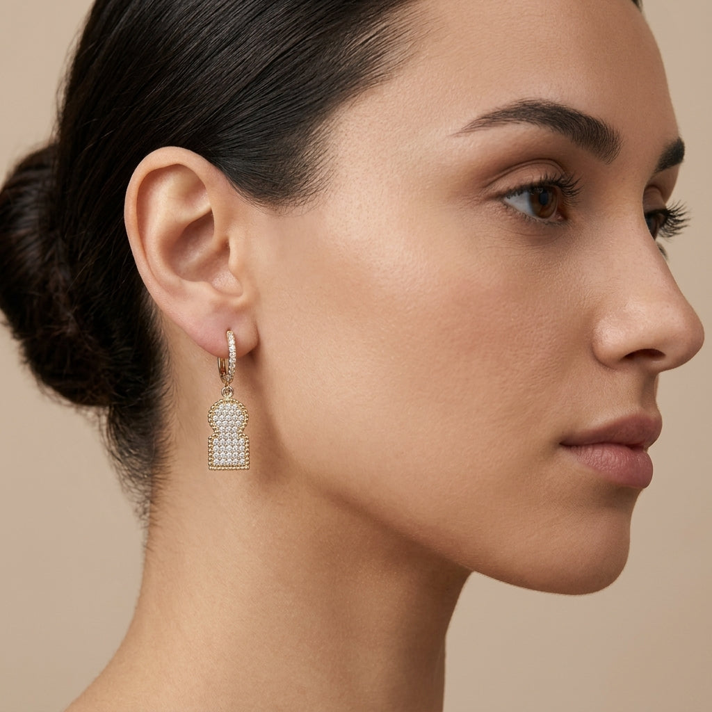 Boucles d'oreilles pendantes en or jaune 18k plaques pavées de pierres - bijou porté par une mannequin