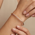 Bracelet jonc fin en or rose 18k serti de pierres - bijou porté par une mannequin