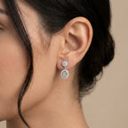 Boucles d'oreilles pendantes en or blanc 18k serties de pierres - bijou porté par une mannequin