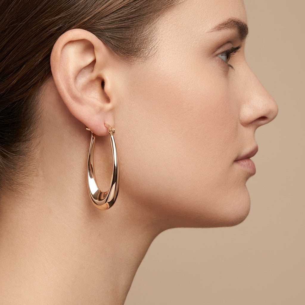 Boucles d'oreilles créoles ovales bombées en or rose 18k - bijou porté par une mannequin