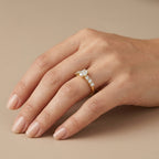 Bague solitaire en or jaune 18k épaulée de pierres - bijou porté par une mannequin