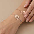 Bracelet chaîne en or rose 18k médaille ronde sertie - bijou porté par une mannequin