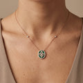 Collier en or rose 18k pendentif rond fleur de lys serti, pierres vertes - bijou porté par une mannequin