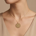 Pendentif médaille ronde ajourée en or jaune 18k gravée d'une sourate - bijou porté par une mannequin