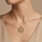 Pendentif médaille ronde ajourée en or jaune 18k gravée d'une sourate - bijou porté par une mannequin