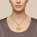 Pendentif médaille ovale en or jaune 18k gravée d'une sourate - bijou porté par une mannequin