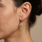 Boucles d'oreilles boulhya en or jaune 18k rosaces serties, franges, pierres vertes - bijou porté par une mannequin