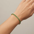 Bracelet rivière en or jaune 18k serti de pierres vertes - bijou porté par une mannequin