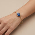 Bracelet jonc ouvert en or jaune 18k pierre bleue cabochon - bijou porté par une mannequin