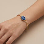Bracelet jonc ouvert en or jaune 18k pierre bleue cabochon - bijou porté par une mannequin