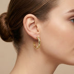 Boucles d'oreilles créoles cloutées en or jaune 18k, motif clash - bijou porté par une mannequin