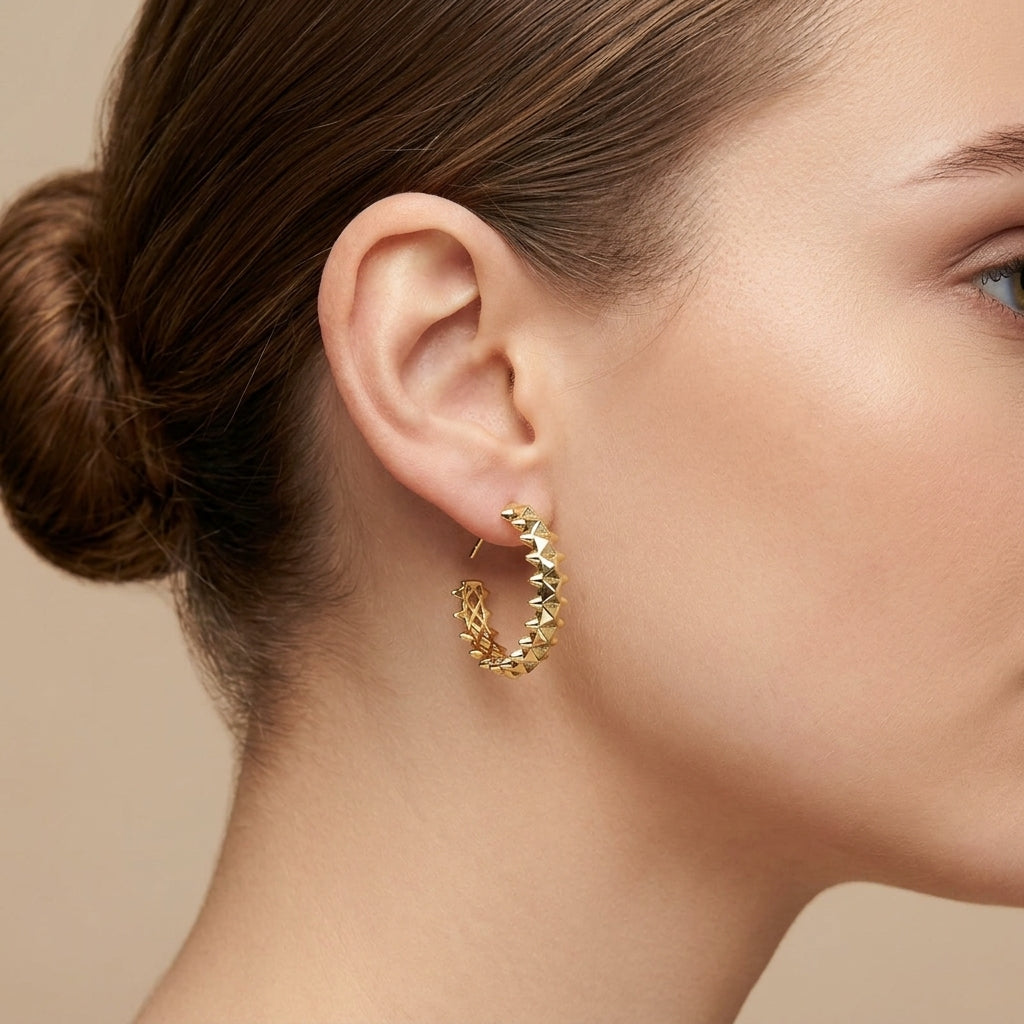 Boucles d'oreilles créoles cloutées en or jaune 18k, motif clash - bijou porté par une mannequin