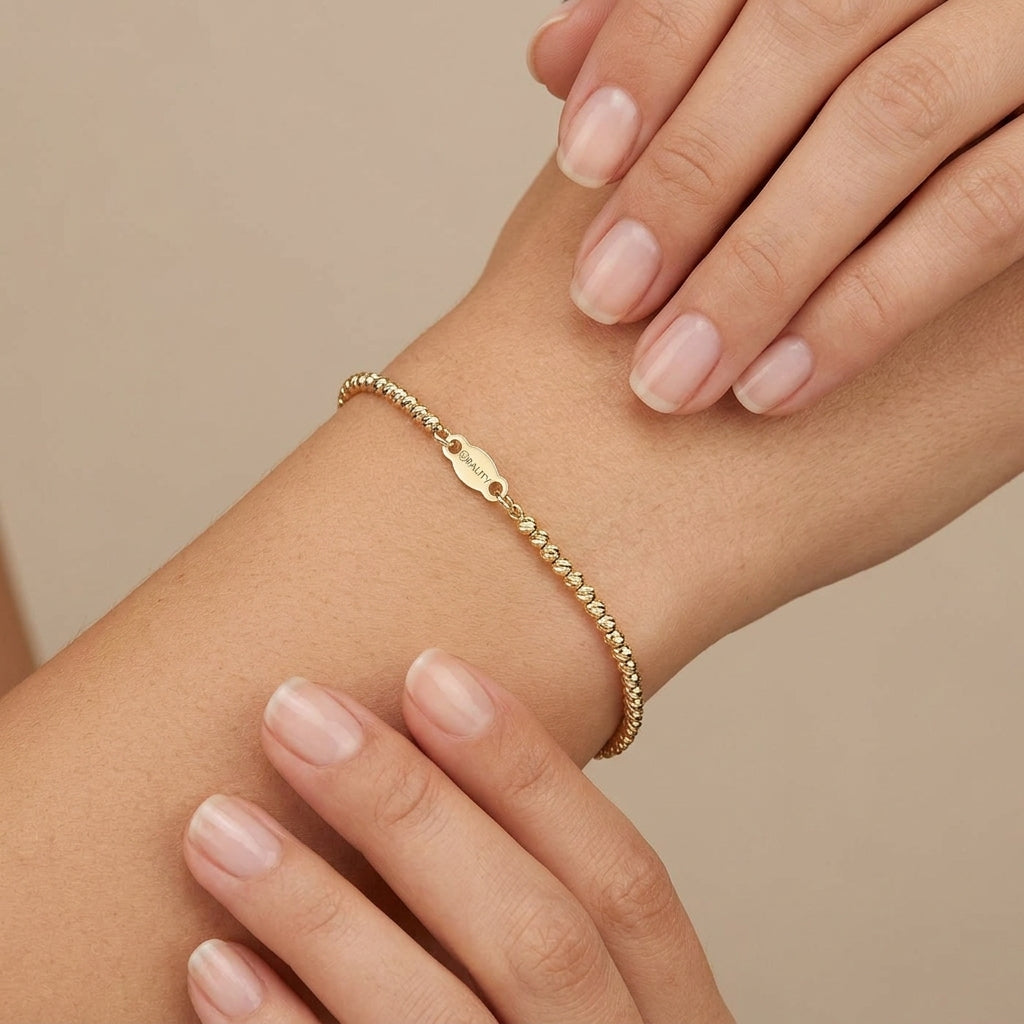 Bracelet boules facettées en or jaune 18k - bijou porté par une mannequin