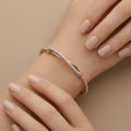 Bracelet jonc en or rose 18k barre pavée de pierres - bijou porté par une mannequin