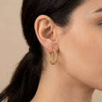 Boucles d'oreilles créoles torsadées en or jaune 18k - bijou porté par une mannequin
