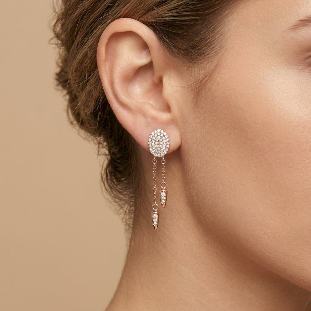 Boucles d'oreilles pendantes en or rose 18k ovales pavés et chaînettes - bijou porté par une mannequin