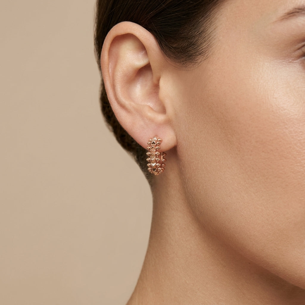 Boucles d'oreilles mini créoles cloutées en or rose 18k, motif clash - bijou porté par une mannequin