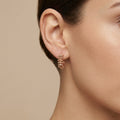 Boucles d'oreilles mini créoles cloutées en or rose 18k, motif clash - bijou porté par une mannequin