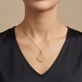 Pendentif khmissa en or jaune 18k gravée d'une sourate - bijou porté par une mannequin