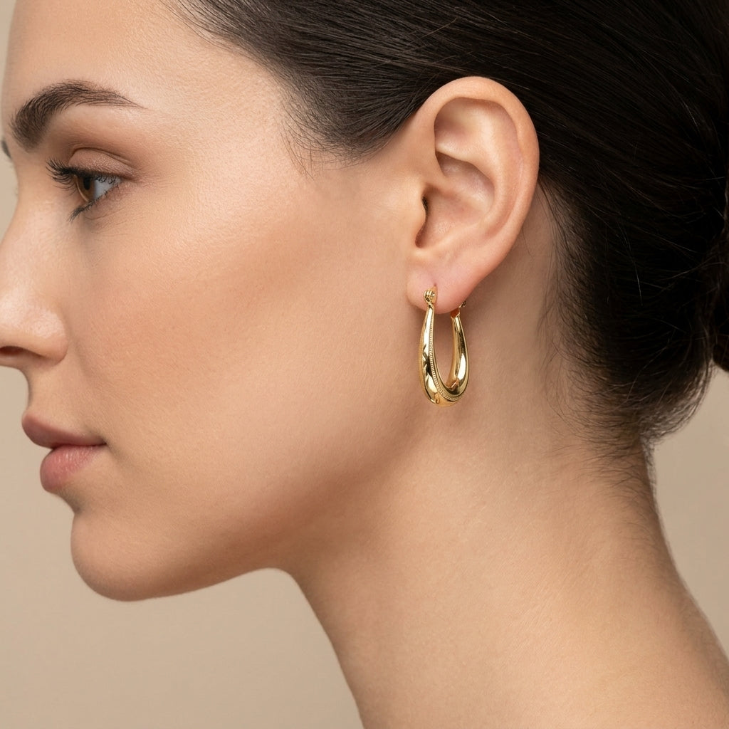 Boucles d'oreilles créoles ovales bombées en or jaune 18k - bijou porté par une mannequin