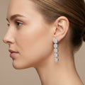 Boucles d'oreilles pendantes en or blanc 18k pastilles pavées - bijou porté par une mannequin
