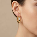 Boucles d'oreilles créoles bombées lisses en or jaune 18k - bijou porté par une mannequin
