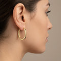 Boucles d'oreilles créoles en or jaune 18k - bijou porté par une mannequin