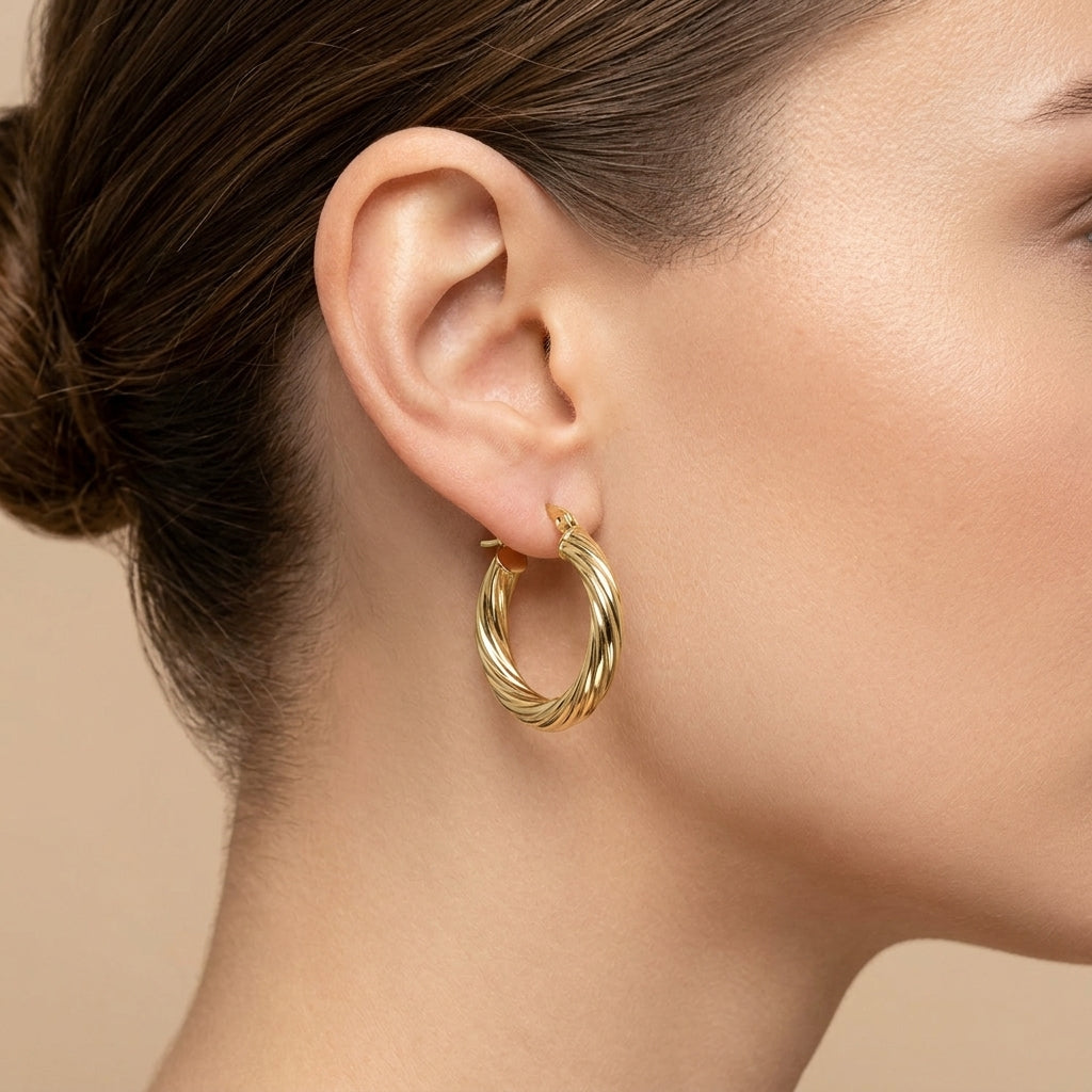 Boucles d'oreilles créoles torsadées en or jaune 18k - bijou porté par une mannequin