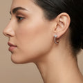 Boucles d'oreilles créoles striées en or rose 18k serties de pierres - bijou porté par une mannequin