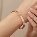 Bracelet jonc en or rose 18k serti de pierres en station - bijou porté par une mannequin