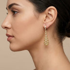 Boucles d'oreilles pendantes gouttes ajourées en or jaune 18k serties de pierres - bijou porté par une mannequin