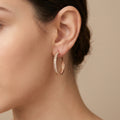 Boucles d'oreilles créoles striées en or rose 18k - bijou porté par une mannequin