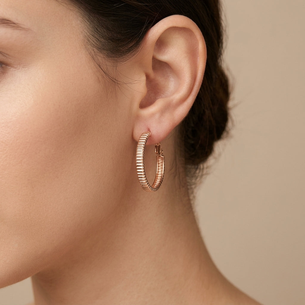 Boucles d'oreilles créoles striées en or rose 18k - bijou porté par une mannequin
